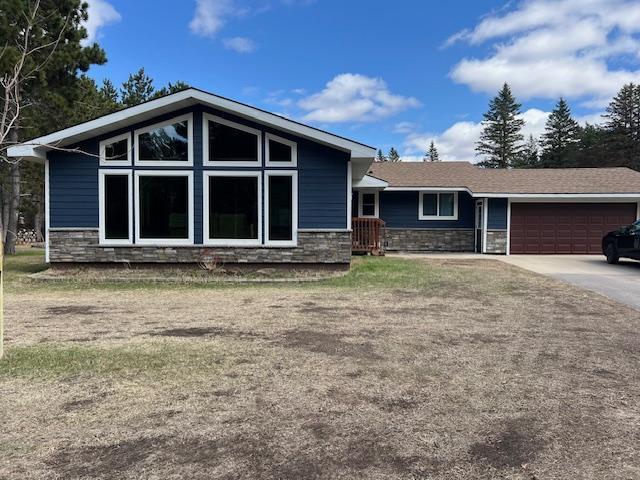 view of front of home with concrete driveway, stone siding, and a garage