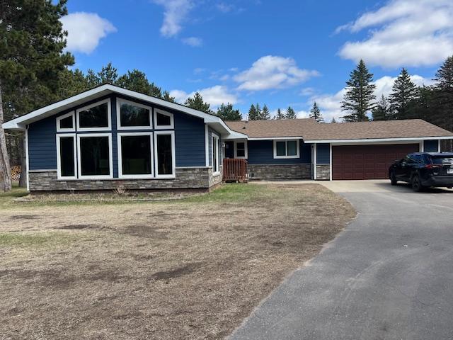 view of front of home featuring driveway, stone siding, and a garage