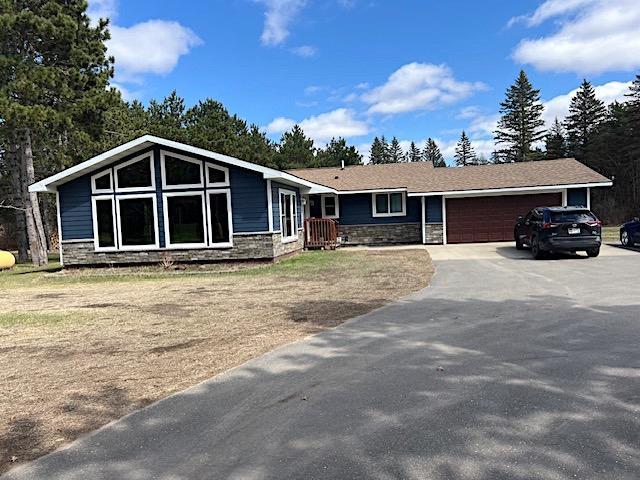 view of front of property with driveway, a garage, and stone siding