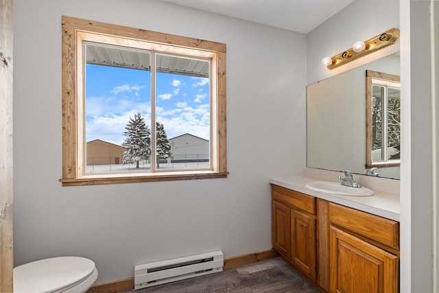 1607 7th Ave, Grand Rapids, MN 55744 - bathroom with a baseboard radiator, toilet, wood finished floors, vanity, and baseboards