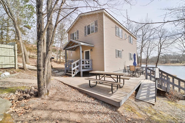rear view of property featuring a deck with water view and outdoor dining space