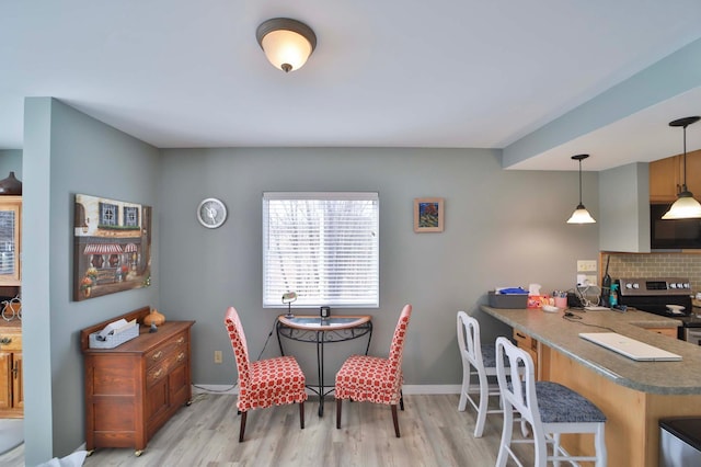 dining space featuring light wood-style flooring and baseboards