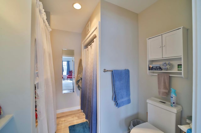 bathroom with wood finished floors, baseboards, toilet, a shower with shower curtain, and visible vents