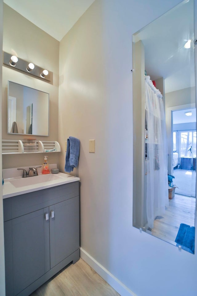 full bath with baseboards, wood finished floors, and vanity
