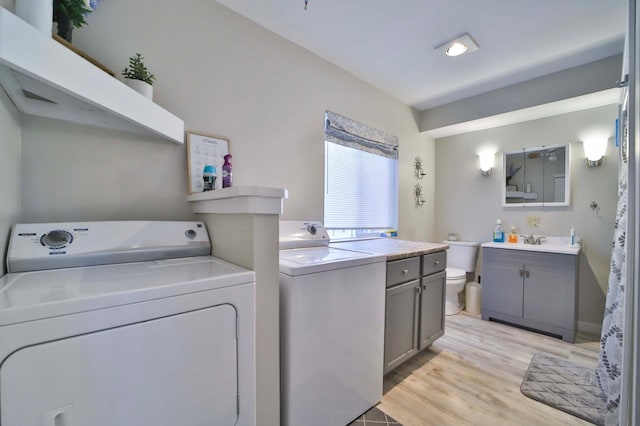 laundry room featuring light wood-type flooring, washer and dryer, and a sink