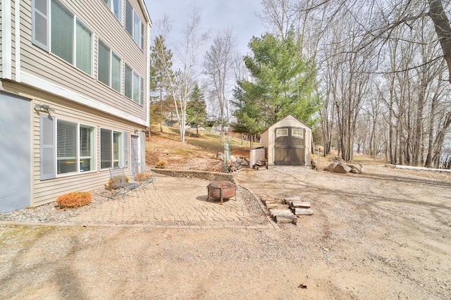 view of yard with an outdoor structure, a fire pit, a storage shed, and a patio