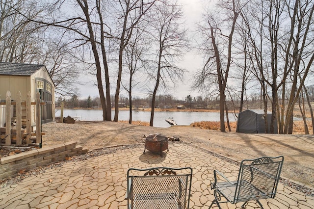view of yard with a water view, an outbuilding, a patio, and an outdoor fire pit