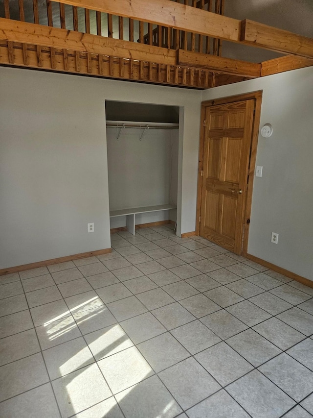 unfurnished bedroom with a closet, baseboards, and light tile patterned floors