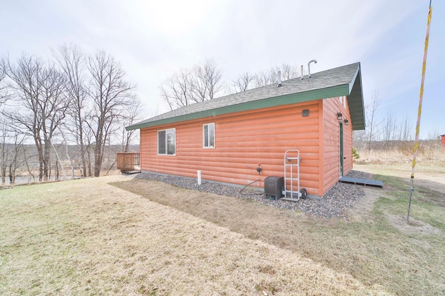 back of house with faux log siding, a lawn, and roof with shingles