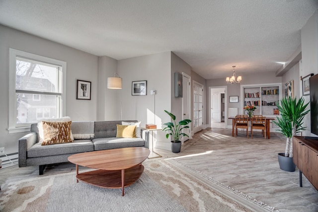 79 Western Ave N Unit 100, Saint Paul, MN 55102 - living room featuring a chandelier, a textured ceiling, a baseboard radiator, and baseboards