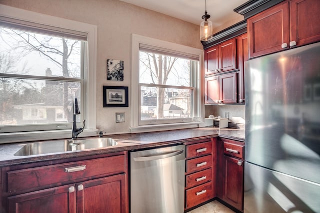 79 Western Ave N Unit 100, Saint Paul, MN 55102 - kitchen featuring stainless steel appliances, dark countertops, reddish brown cabinets, a sink, and decorative light fixtures