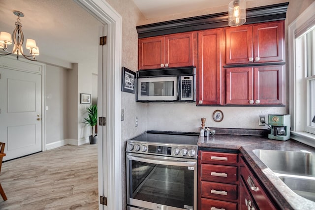79 Western Ave N Unit 100, Saint Paul, MN 55102 - kitchen featuring stainless steel appliances, reddish brown cabinets, a chandelier, and dark countertops