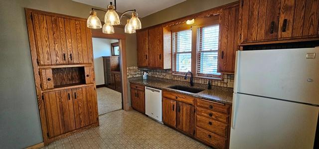 502 Park St S, Fairfax, MN 55332 - kitchen with white appliances, a sink, brown cabinetry, and tasteful backsplash