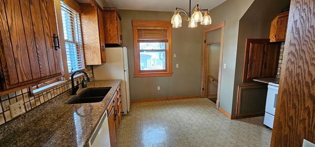 502 Park St S, Fairfax, MN 55332 - kitchen with a sink, baseboards, light flooring, a chandelier, and brown cabinetry