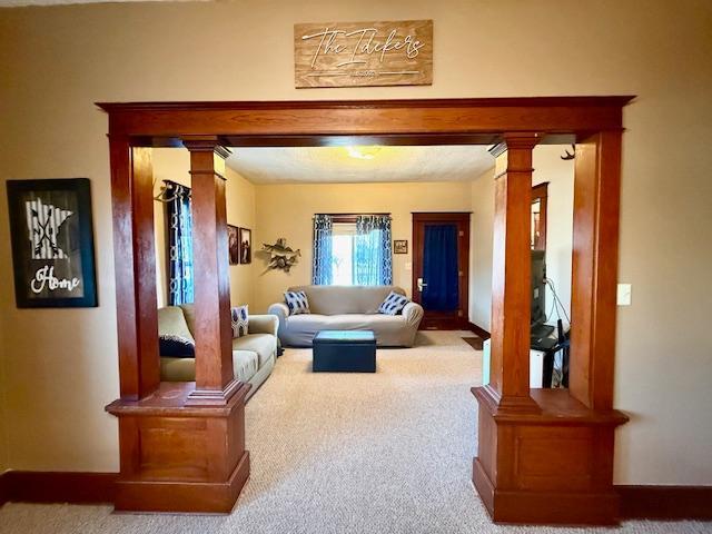 living area with decorative columns and carpet floors