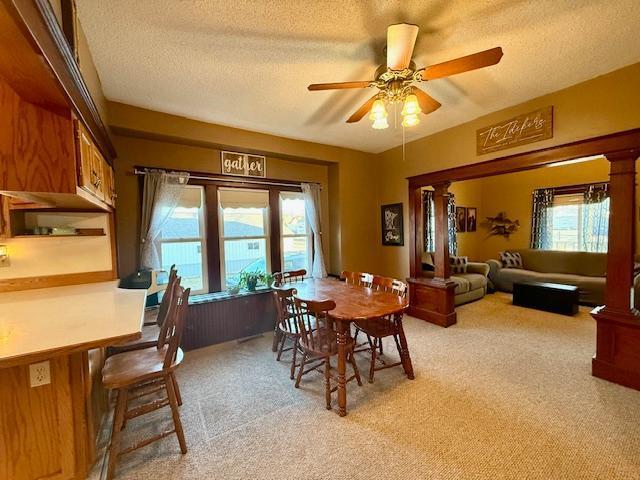 dining space with light carpet, a healthy amount of sunlight, and ceiling fan