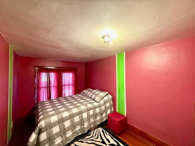 bedroom with a textured ceiling and wood finished floors