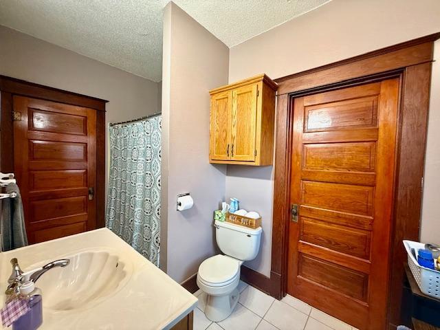 bathroom featuring a textured ceiling, toilet, tile patterned flooring, and vanity