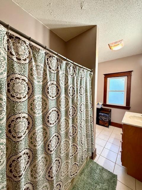 full bath with vanity, a shower with curtain, a textured ceiling, tile patterned flooring, and baseboards