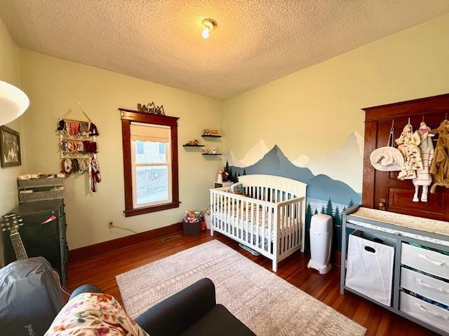 bedroom with a textured ceiling, baseboards, and wood finished floors