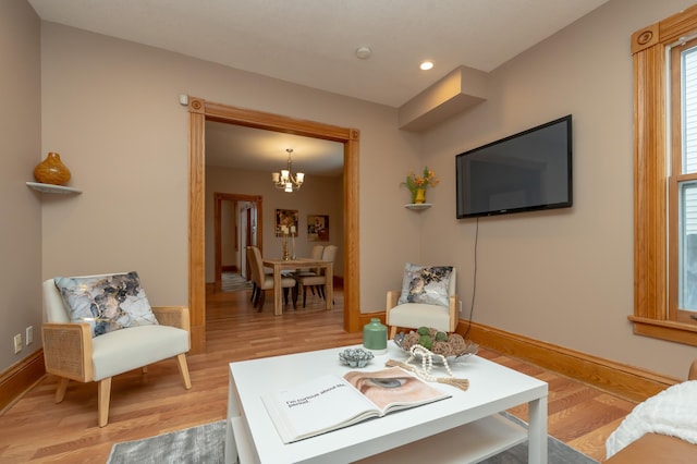 living room featuring light wood-style floors, a notable chandelier, baseboards, and recessed lighting