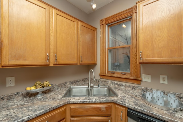 kitchen with stone counters, a sink, and dishwashing machine