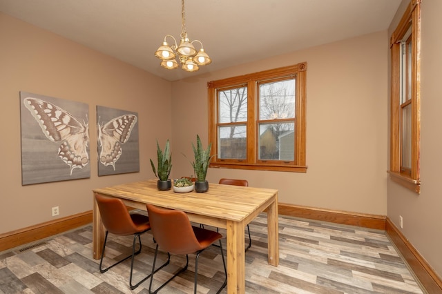 dining area featuring a chandelier, light wood-style flooring, and baseboards