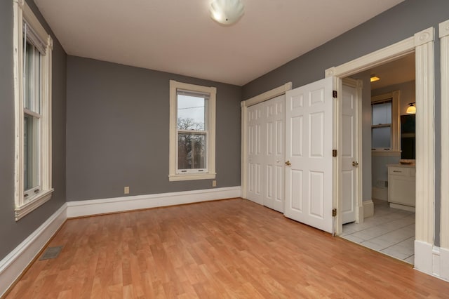 unfurnished bedroom with wood finished floors, baseboards, a closet, and visible vents