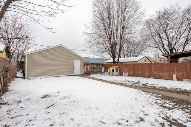 yard covered in snow with a fenced backyard and an outdoor structure