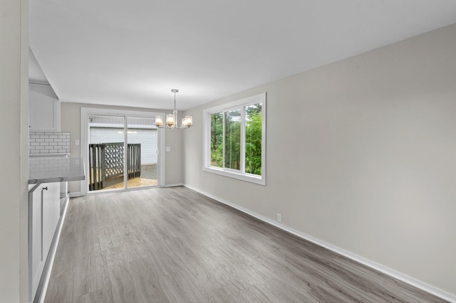 3401 Meadow Ln, Minnetonka, MN 55345 - unfurnished living room with wood finished floors, a chandelier, and baseboards