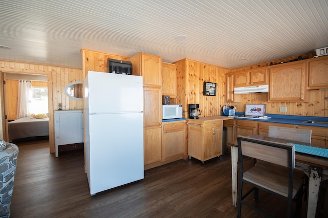 kitchen featuring wood walls, white appliances, dark wood finished floors, and under cabinet range hood