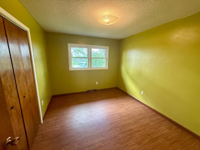 68680 470th St, Wellington Twp, MN 55332 - unfurnished bedroom with wood finished floors, a closet, a textured ceiling, and baseboards