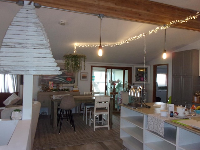 kitchen featuring healthy amount of natural light, open shelves, wood finished floors, pendant lighting, and lofted ceiling