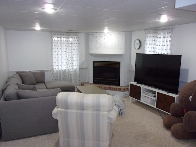 living room with a drop ceiling, a fireplace, and carpet floors