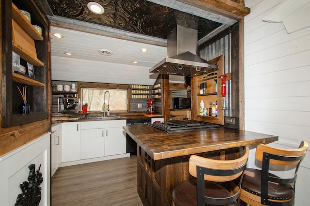 bar featuring stainless steel gas stovetop, dishwasher, a sink, island range hood, and dark wood-style floors