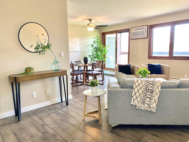 living area featuring baseboards, ceiling fan, an AC wall unit, and wood finished floors