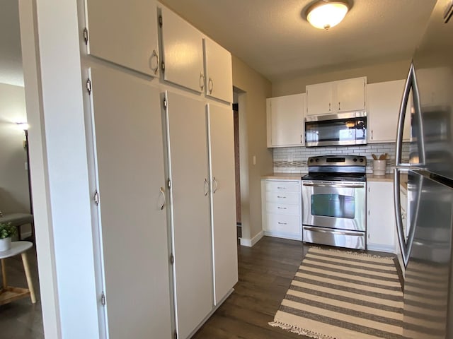 kitchen with white cabinets, appliances with stainless steel finishes, light countertops, dark wood finished floors, and tasteful backsplash