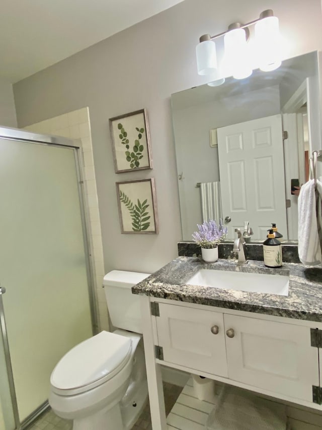 bathroom featuring vanity, toilet, and a stall shower