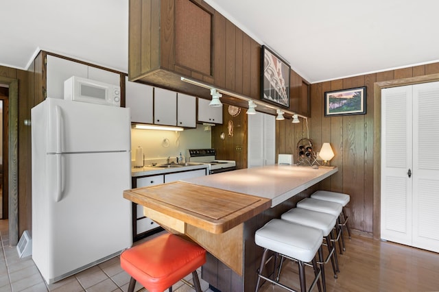 1109 Hamilton St, Saint Croix Falls, WI 54024 - kitchen featuring freestanding refrigerator, range with electric cooktop, wooden walls, a kitchen breakfast bar, and a peninsula
