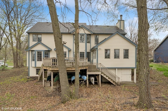 back of house featuring a wooden deck, stairs, a chimney, and roof with shingles