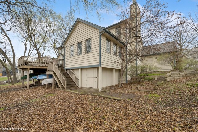 back of property with stairs, a chimney, and a deck