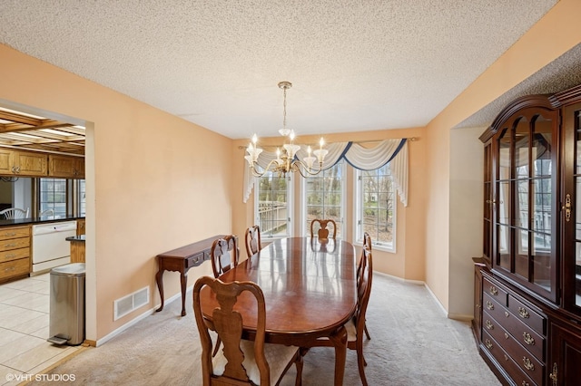 dining room featuring visible vents, baseboards, light colored carpet, a textured ceiling, and a chandelier