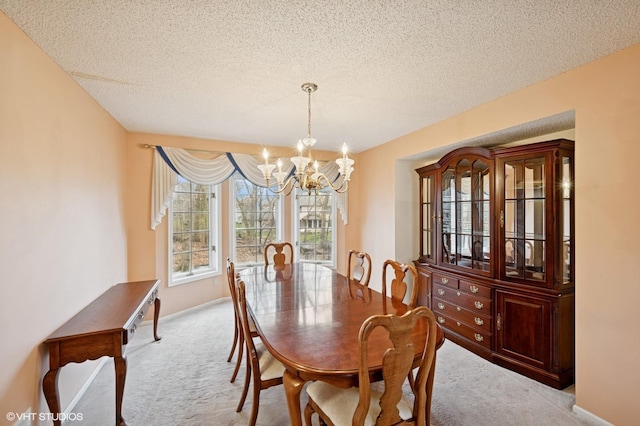carpeted dining area with baseboards, a textured ceiling, and a notable chandelier