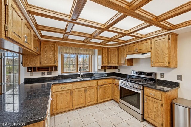 kitchen featuring stainless steel range with gas cooktop, under cabinet range hood, brown cabinets, a sink, and coffered ceiling