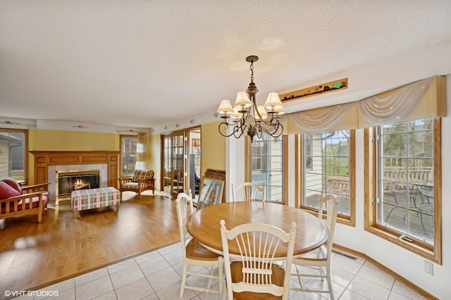 dining space featuring light tile patterned floors, plenty of natural light, a textured ceiling, and a notable chandelier