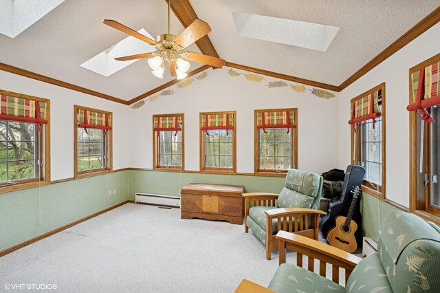 sitting room featuring carpet flooring, a baseboard heating unit, ornamental molding, and a wealth of natural light