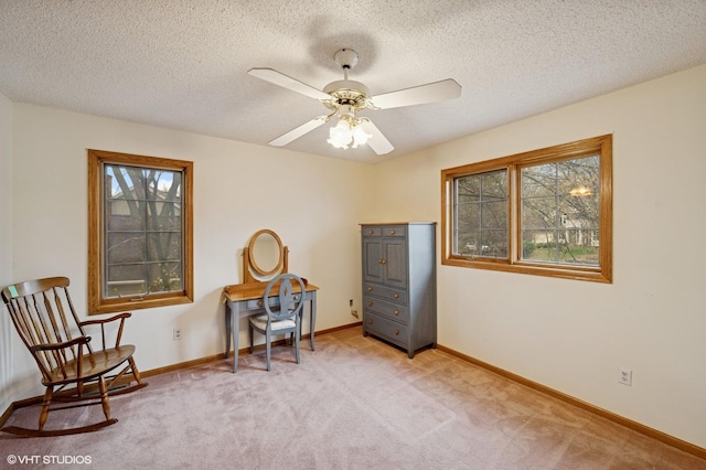 living area featuring baseboards, ceiling fan, and light colored carpet