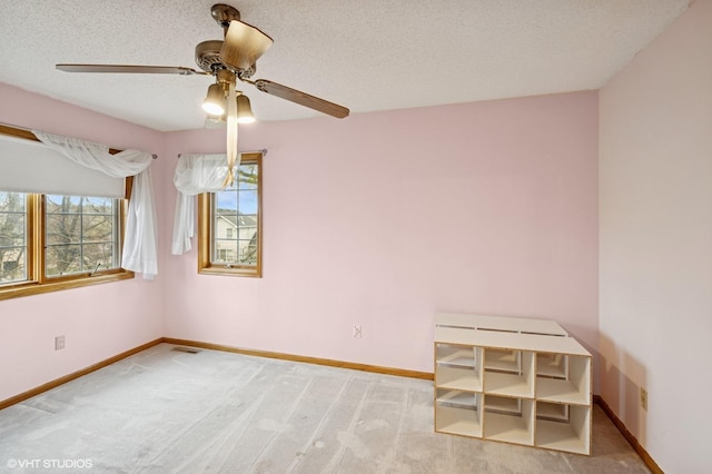 unfurnished room featuring baseboards, a textured ceiling, ceiling fan, and light carpet