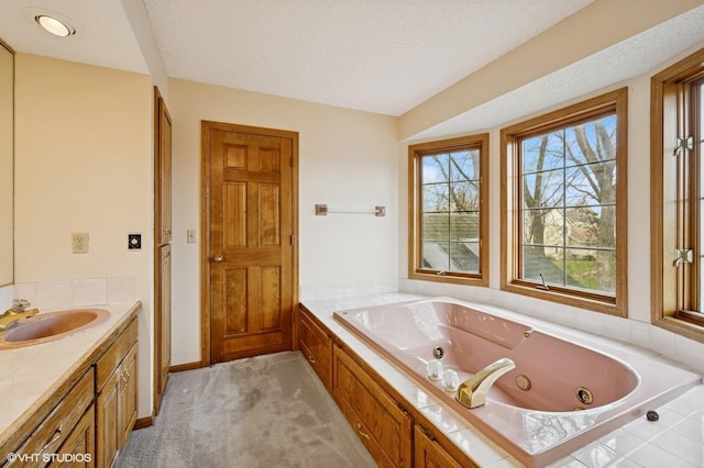 full bathroom with a jetted tub, vanity, and a textured ceiling