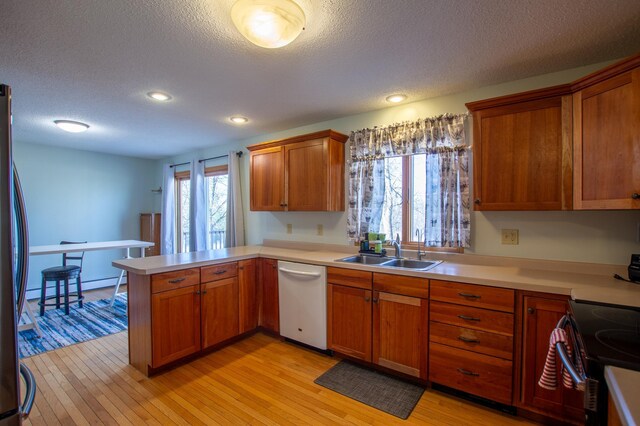 17367 Gull Lake Loop Rd NE, Bemidji, MN 56601 - kitchen with a sink, appliances with stainless steel finishes, a peninsula, a textured ceiling, and light wood-style flooring